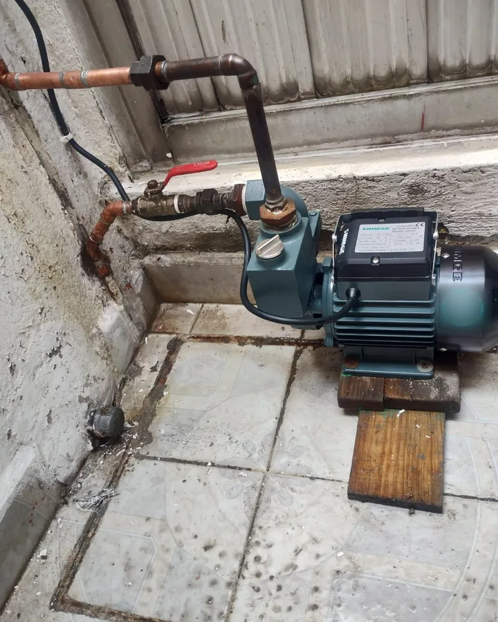 Bomba de agua instalada en un patio con tubería de cobre y válvulas