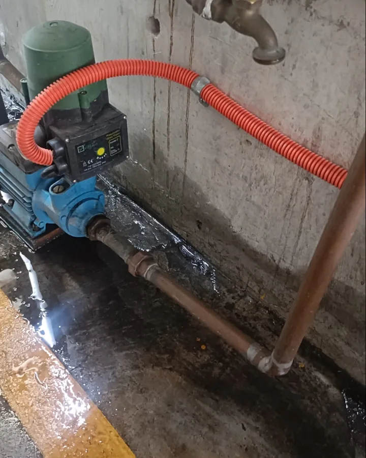 Presurizador de agua con manguera corrugada naranja en un cuarto de máquinas