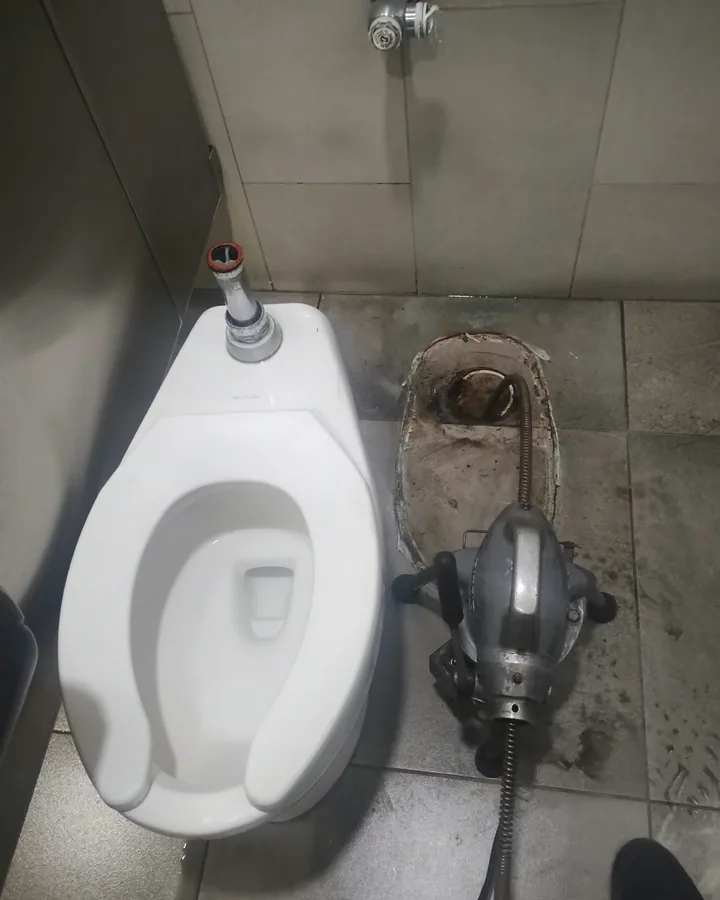 WC comercial retirado y máquina de sonda junto al desagüe del piso