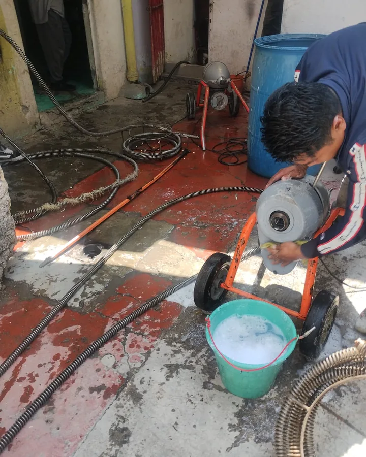 Plomero de Plomería Torres manejando una máquina de sonda de tambor en un patio