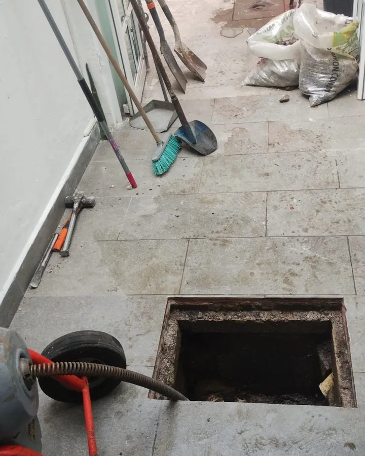 Máquina de sonda junto a un registro de drenaje abierto en el patio de una casa
