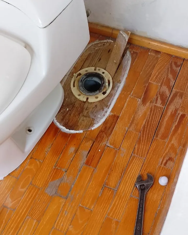 Brida de desagüe en piso de madera lista para instalar un WC nuevo
