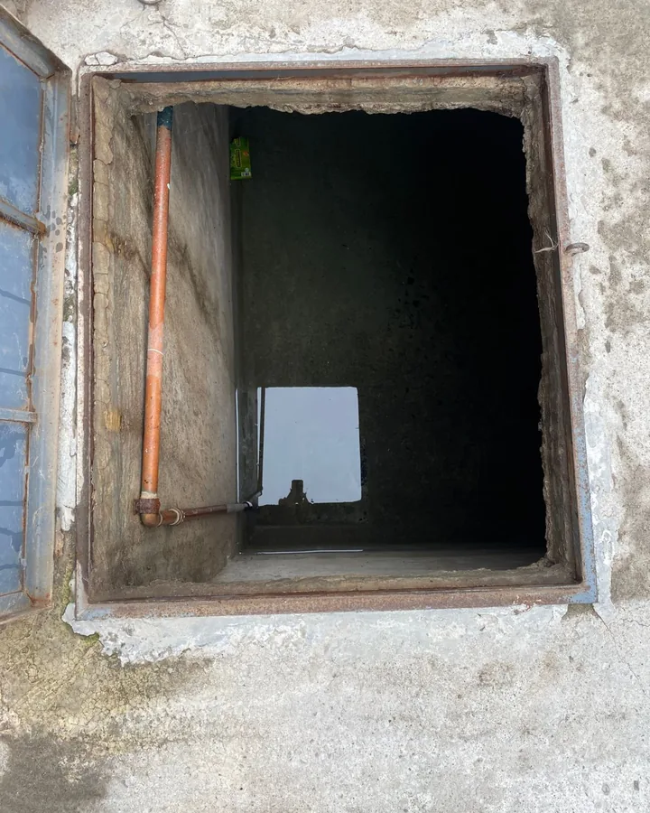 Registro de cisterna abierto con la tubería de entrada a la vista