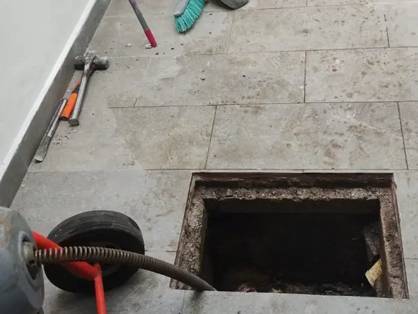 Máquina de sonda junto a un registro de drenaje abierto en un patio