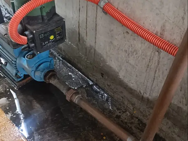 Bomba de agua con control de presión y manguera corrugada instalada junto a la llave