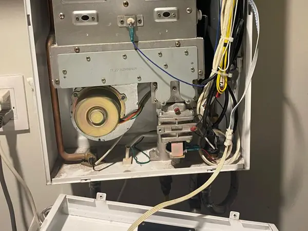 Calentador de paso abierto con el ventilador y la válvula de gas a la vista durante la reparación