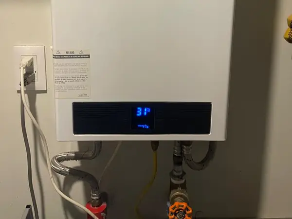 Pantalla de un boiler de paso encendido con sus conexiones de agua y gas