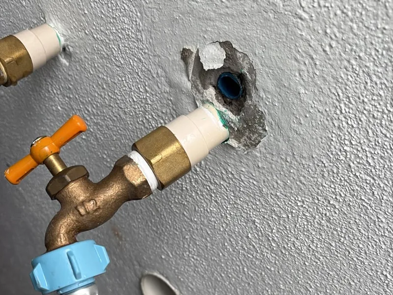 Plomero conectando una llave nueva en el muro después de reparar una fuga