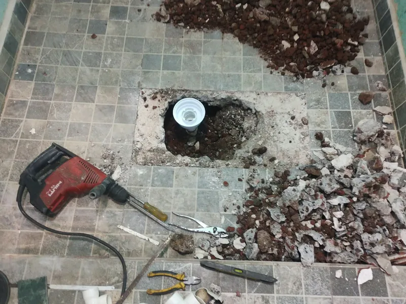 Piso de baño abierto con rotomartillo para la instalación sanitaria de una coladera nueva