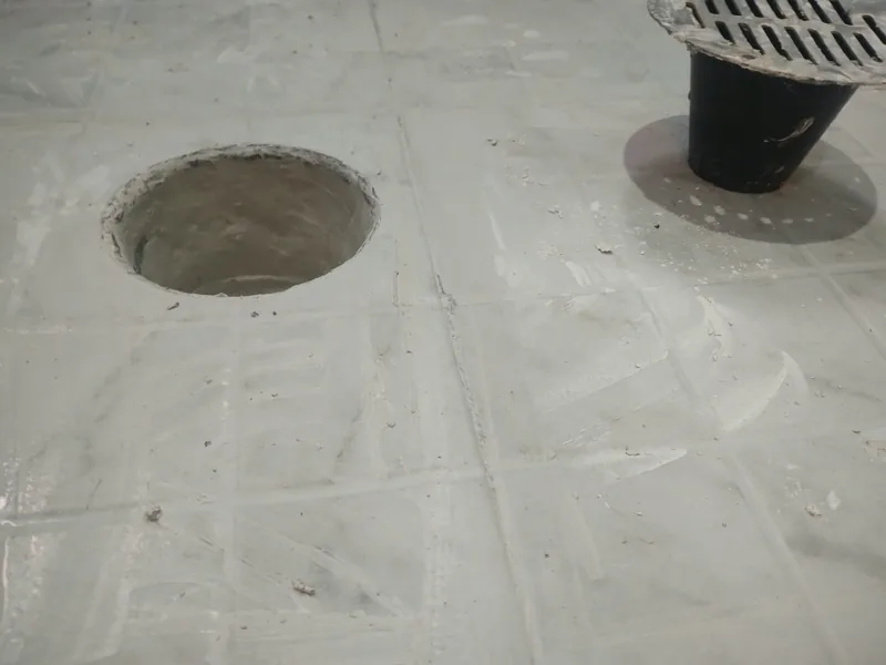 Salida de desagüe preparada en un piso nuevo junto a una coladera