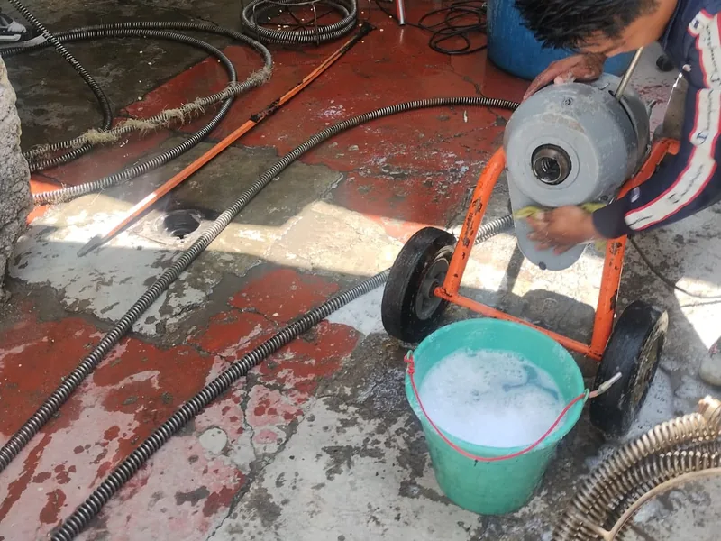 Plomero urgente de Plomería Torres usando una máquina de sonda de tambor en un patio