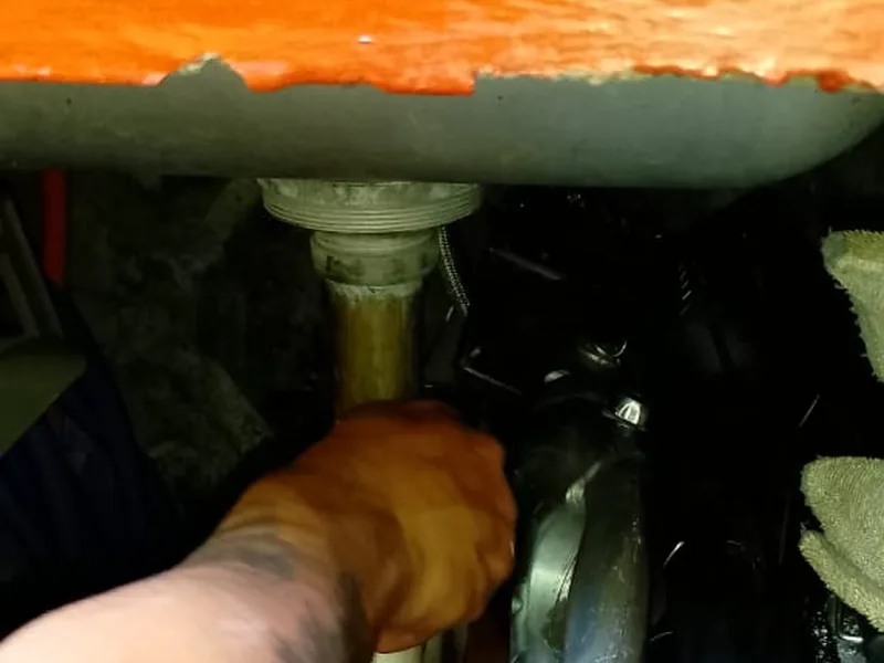Plomero reparando una conexión debajo de una tarja de cocina