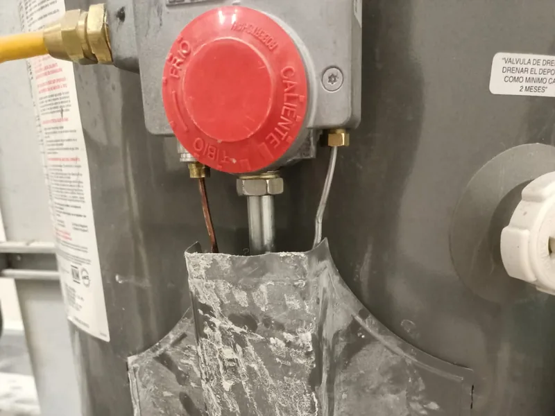 Control de gas con perilla roja de un boiler de depósito durante la reparación